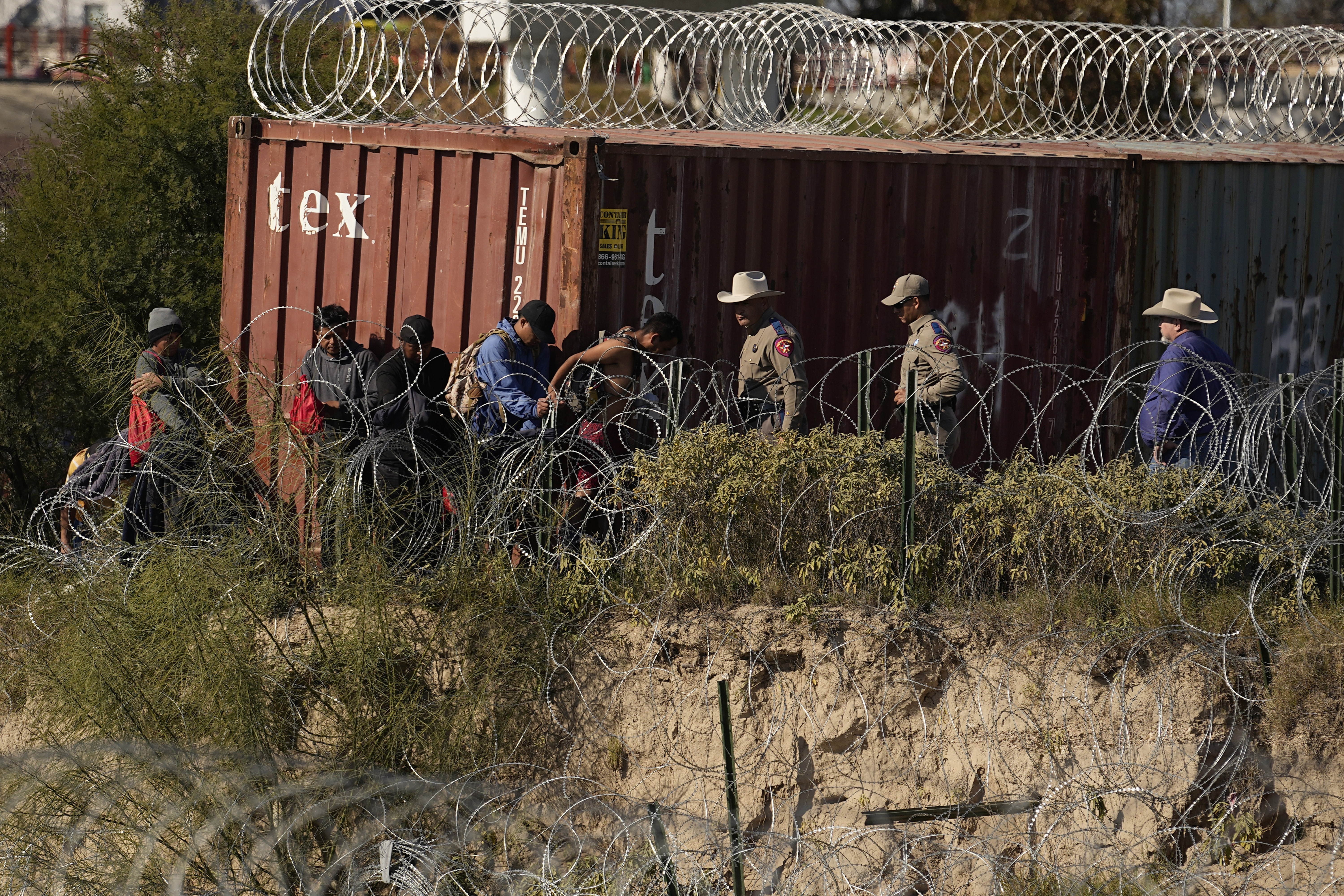 Texas Department of Public Safety troopers help guide migrants to a processing area after they crossed the Rio Grande from Mexico into the U.S., Wednesday, Jan. 3, 2024, in Eagle Pass, Texas. According to U.S. officials, a Mexican enforcement surge, including forcing migrants off of freight trains and flying and busing migrants to the southern part of country, has contributed to a sharp drop in illegal entries to the U.S. in recent weeks. (AP Photo/Eric Gay)
