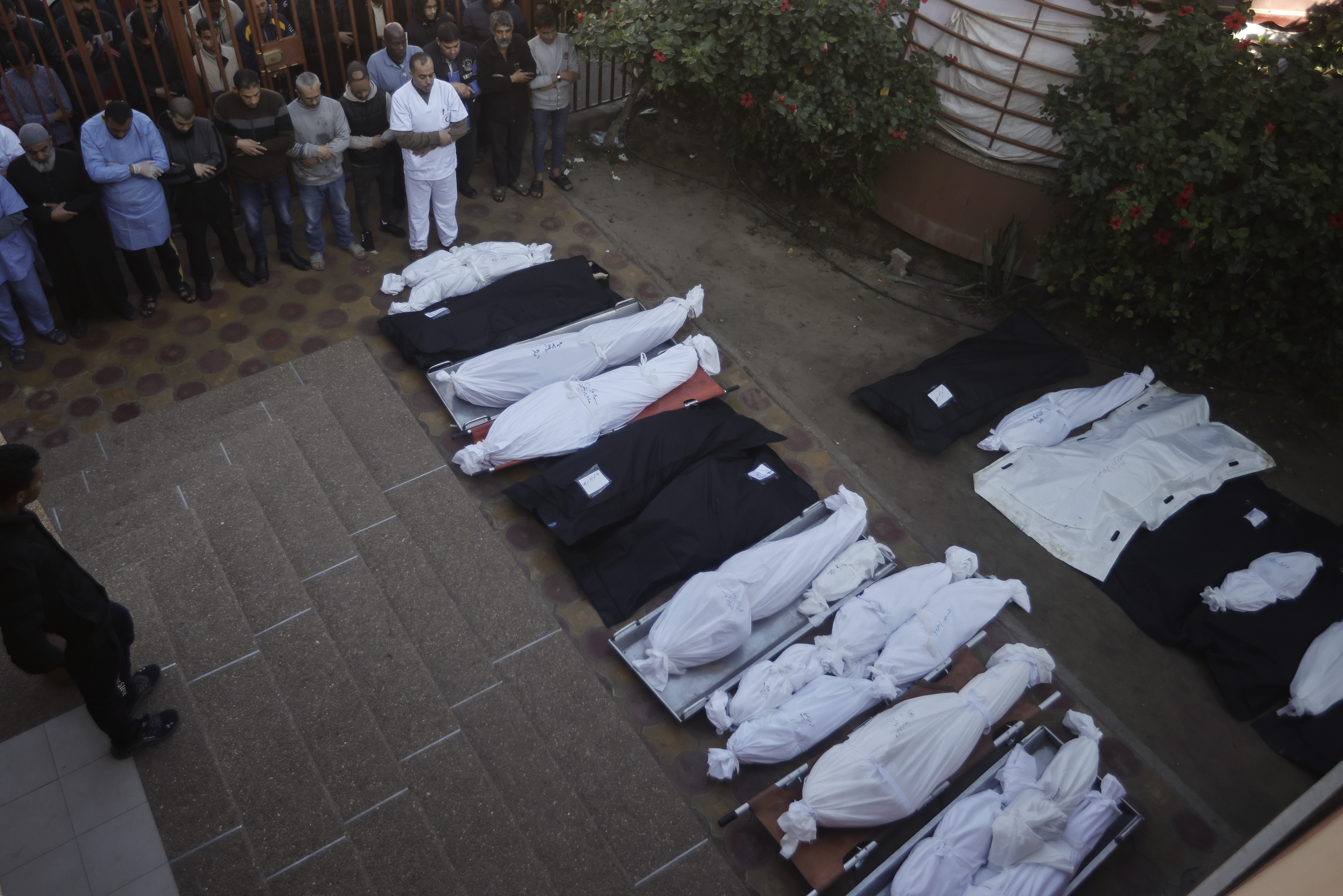 Palestinians pray near the wrapped bodies of relatives killed in the Israeli bombardment of the Gaza Strip, outside a morgue in Khan Younis on Sunday, Jan. 7, 2024. (AP Photo/Mohammed Dahman)